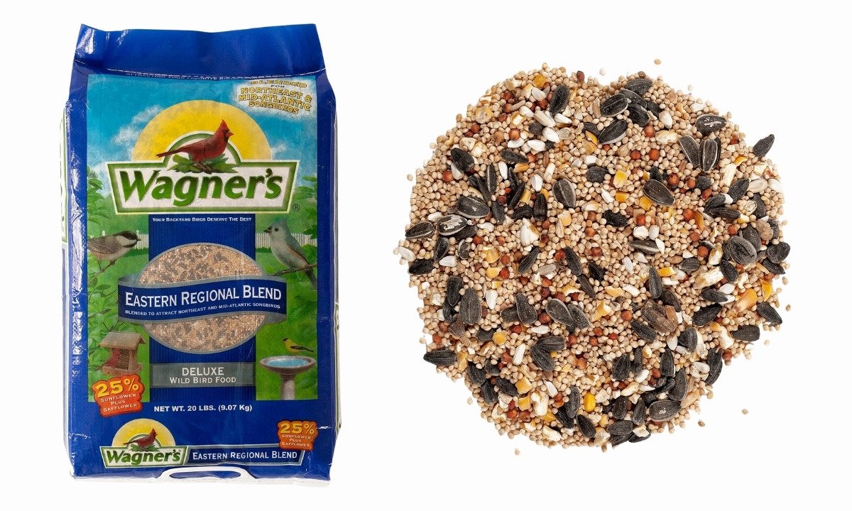 A 20-pound blue bag of Wagner's Eastern Regional Wild Bird Food next to a pile of the seed mix, which contains sunflower seeds, millet, and cracked corn